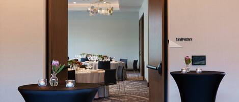 Un hall de hotel con mostrador de recepción, una zona de estar con mesas y sillas, y un cartel en la pared que dice "SYMPHONY".