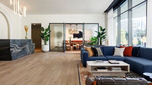 A modern living room with a blue sofa, a coffee table, and a large window.