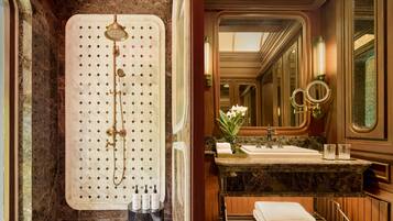 A luxurious bathroom with a freestanding shower, marble countertops, a vanity with a sink, and a large mirror.