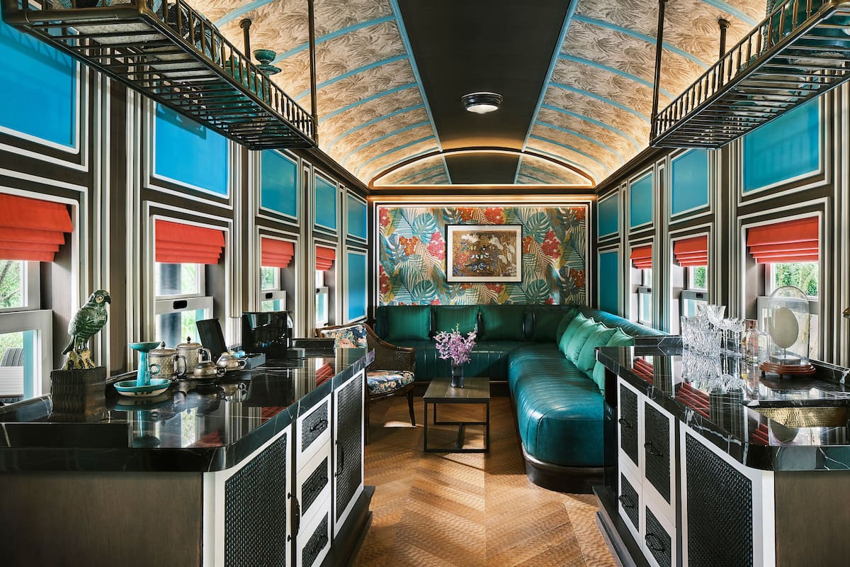 A modern interior with a teal sofa, a coffee table, and a kitchen area.