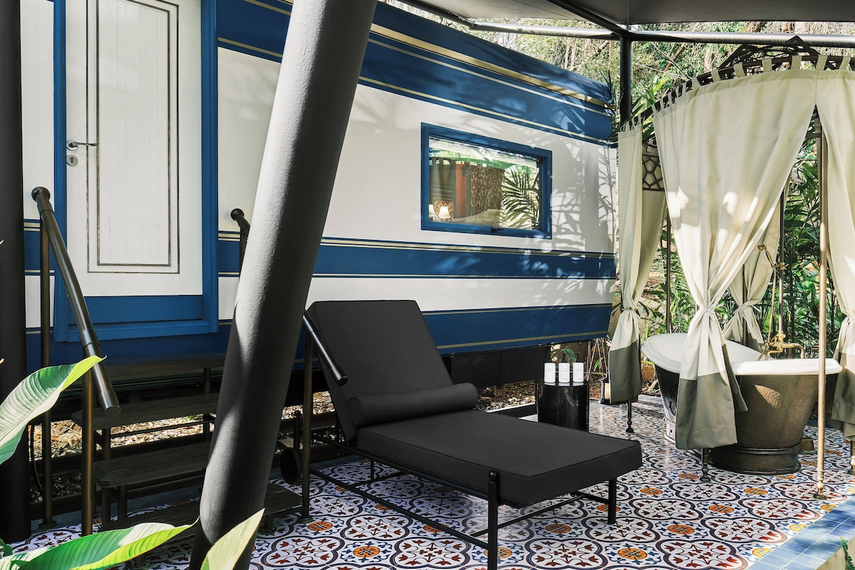 A covered outdoor seating area with a black lounge chair, a small table, and a canopy.