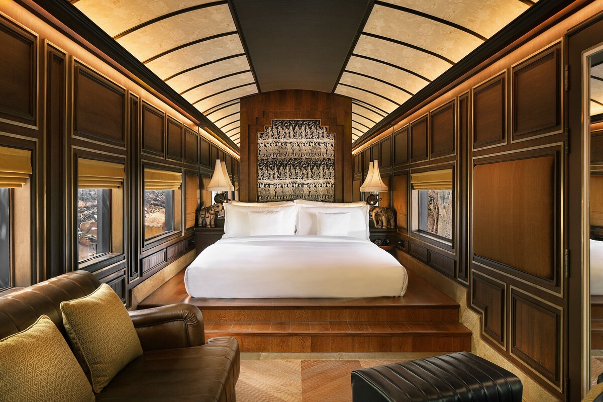 A luxurious bedroom with a large bed, a sofa, and a view of a rocky landscape.