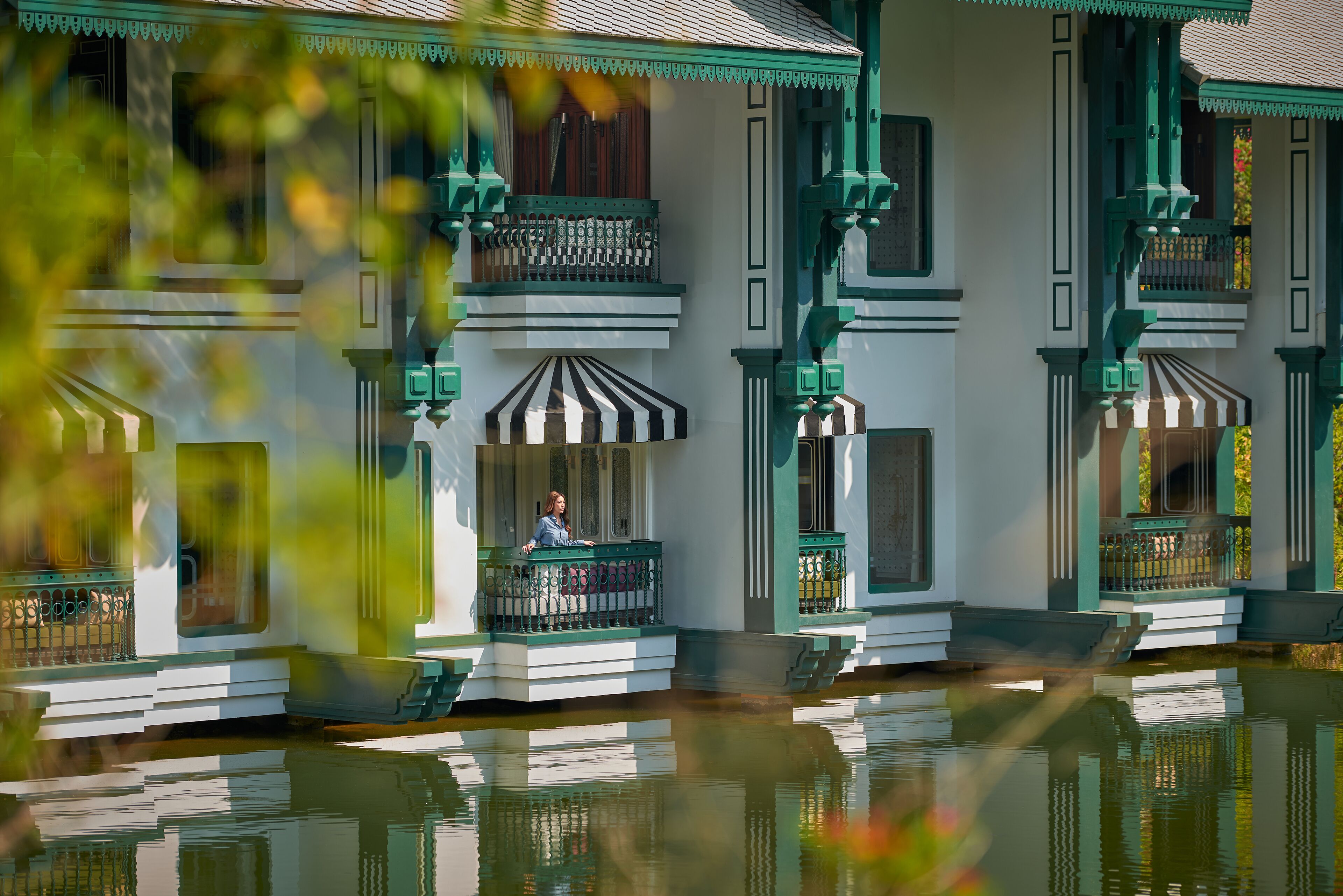 Un edificio tradicional con un balcón y su reflejo en el agua.