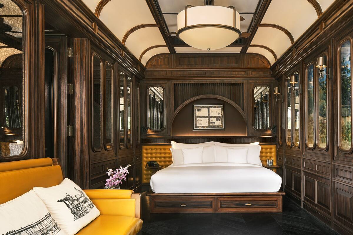 A luxurious bedroom with a large bed, a yellow sofa, and a chandelier.