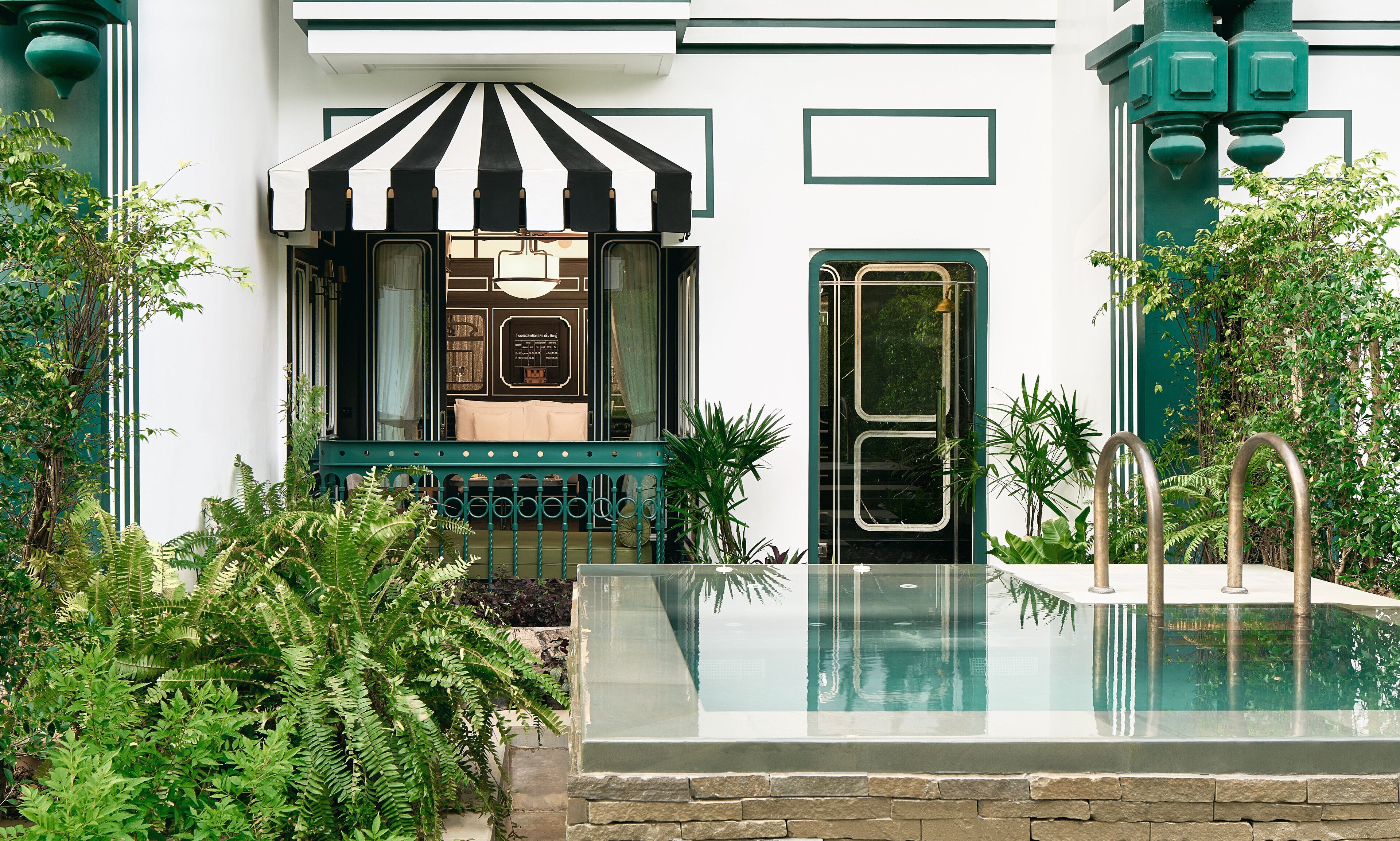 A pool area with a glass barrier, a striped awning, and a door with a window.