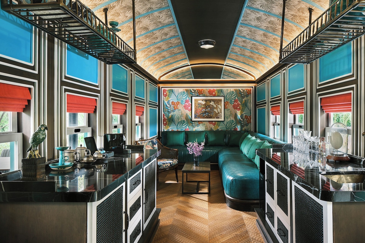 A modern interior with a teal sofa, a coffee table, and a kitchen area.