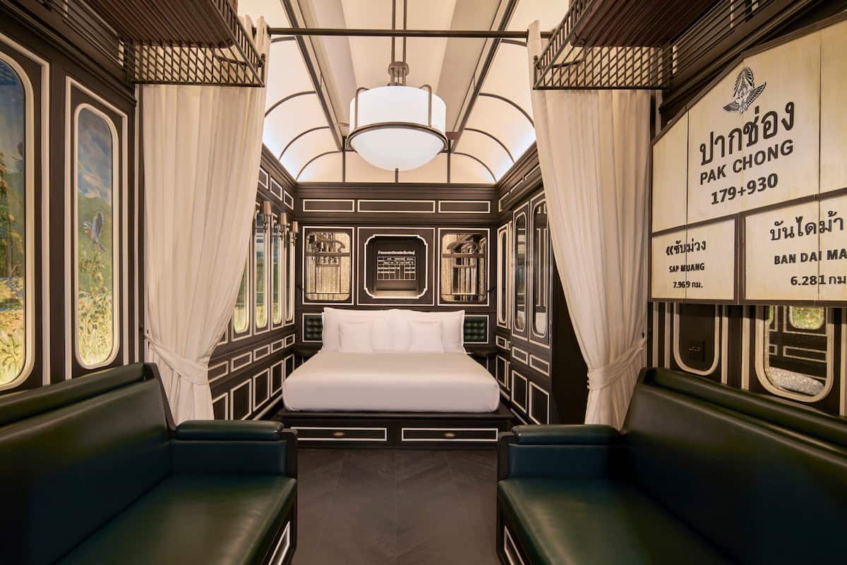 A train carriage bedroom with a bed, curtains, and a mural.
