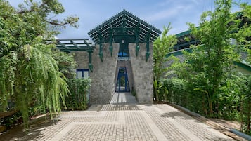 A traditional building with a stone entrance and a blue gate, surrounded by lush greenery.