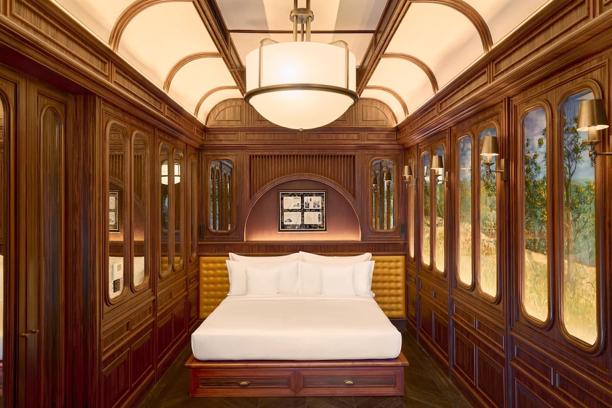 A luxurious bedroom with a large bed, wooden paneling, and large windows with views.