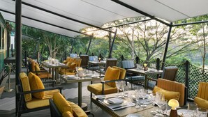 An outdoor dining area with tables set for a meal, surrounded by lush greenery and trees. - Intercontinental Khao Yai Resort by IHG (Pak Chong)