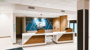 A modern reception area with a check-in counter, a blue and white geometric wall design, and a wooden reception desk.