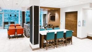 Une salle de réunion moderne, dotée d’une grande table, de chaises de couleur turquoise et d’un mur décoratif en bois.