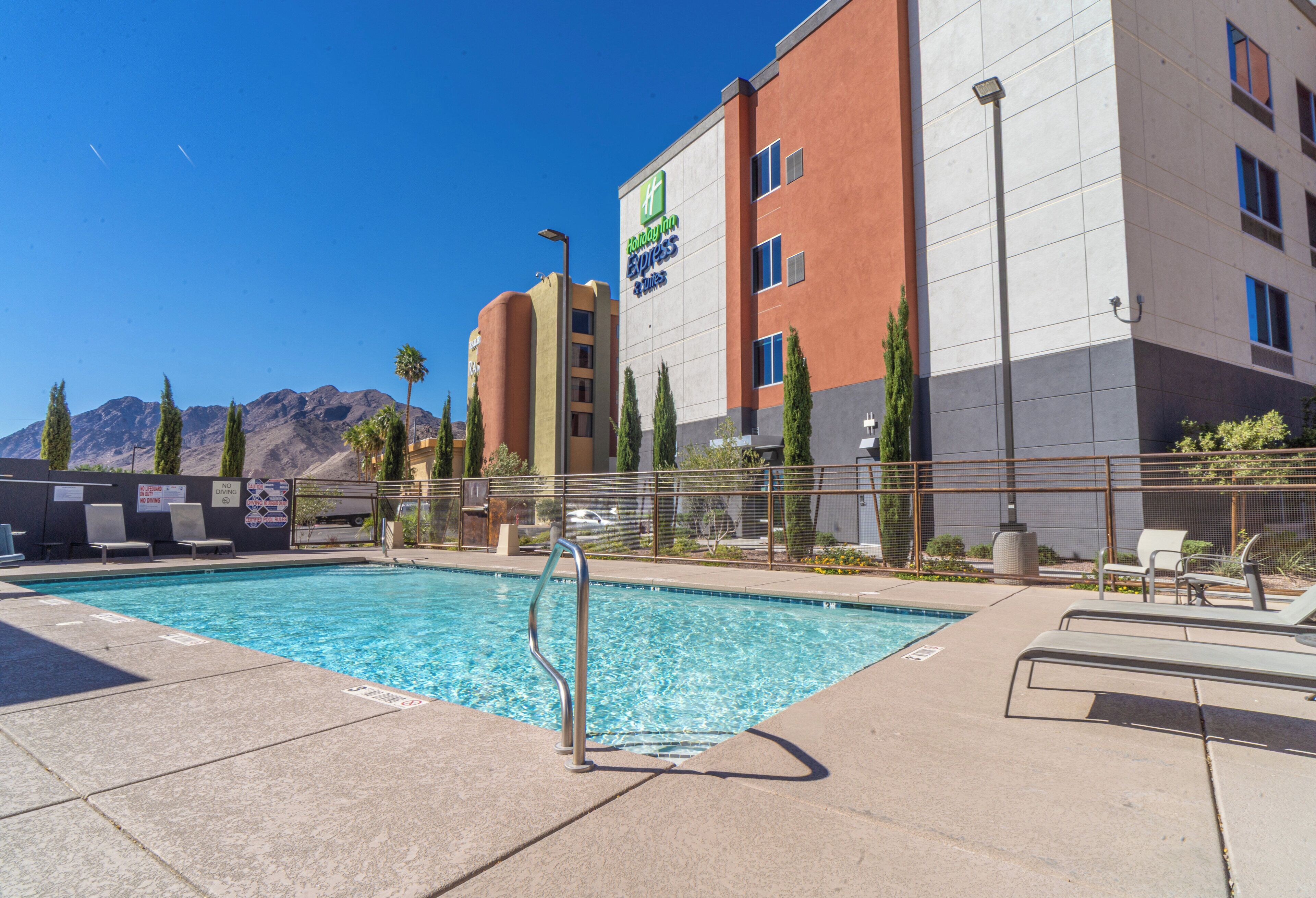 A hotel with a pool, outdoor seating, and a mountainous backdrop.