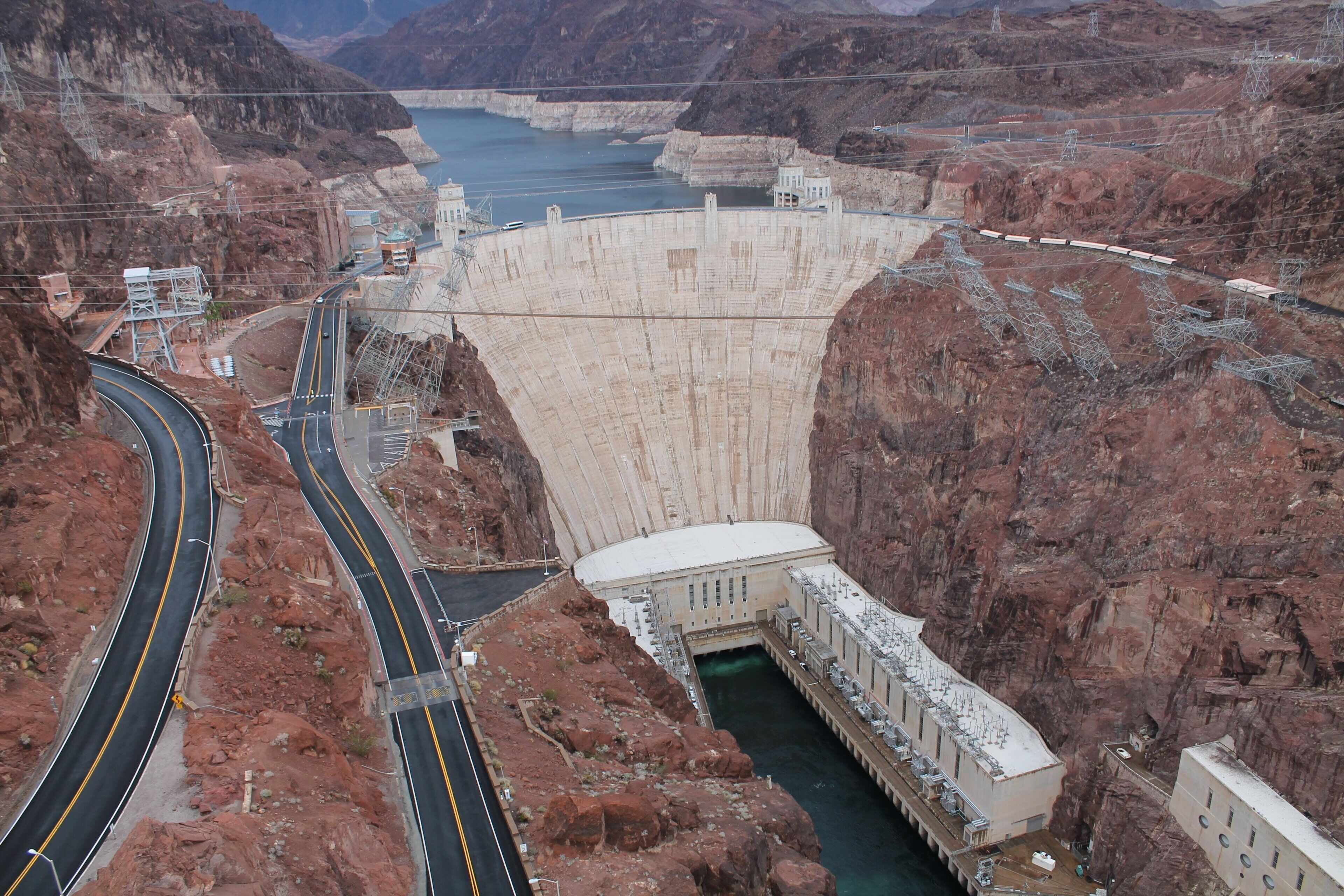 A large dam with a road passing through it, a waterway, and buildings on the dam's structure.