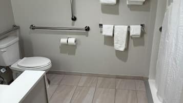 Een badkamer met een toilet, een handgreep en meerdere handdoeken op een rek.