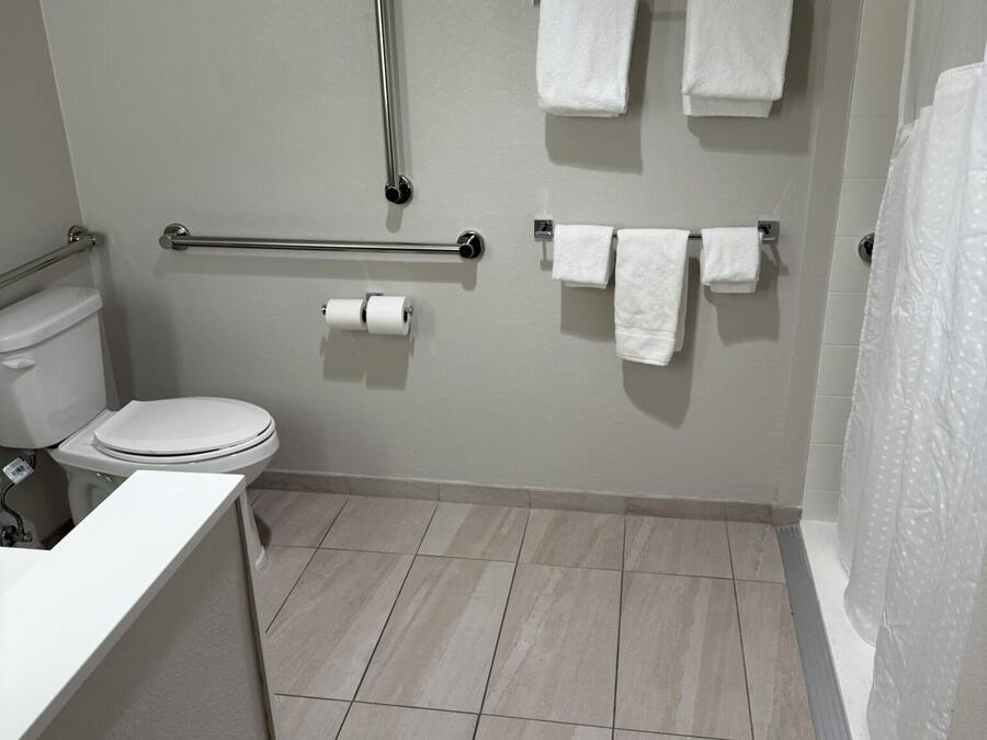 Een badkamer met een toilet, een handgreep en meerdere handdoeken op een rek.
