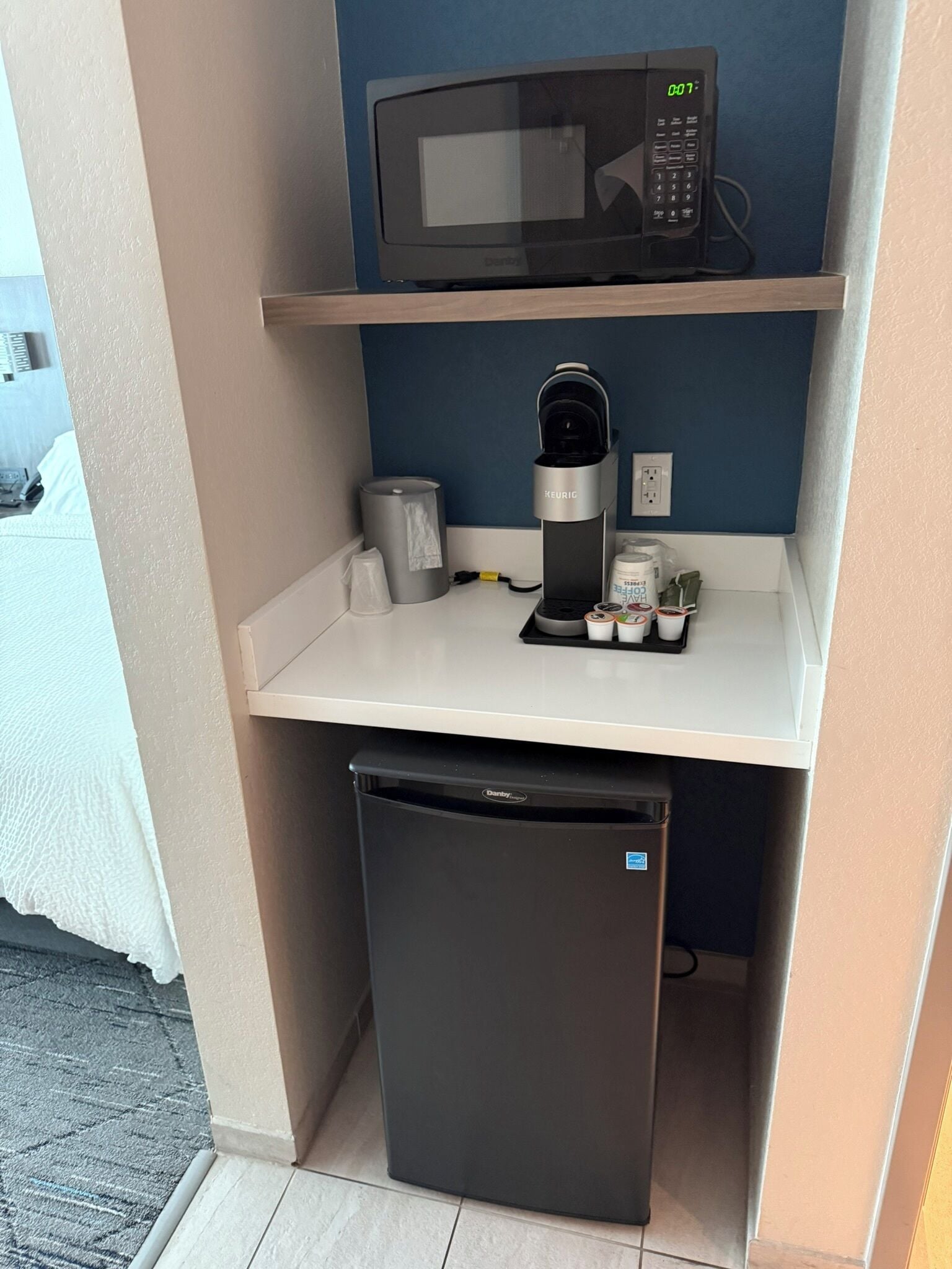 A compact kitchenette with a microwave, coffee maker, and refrigerator.