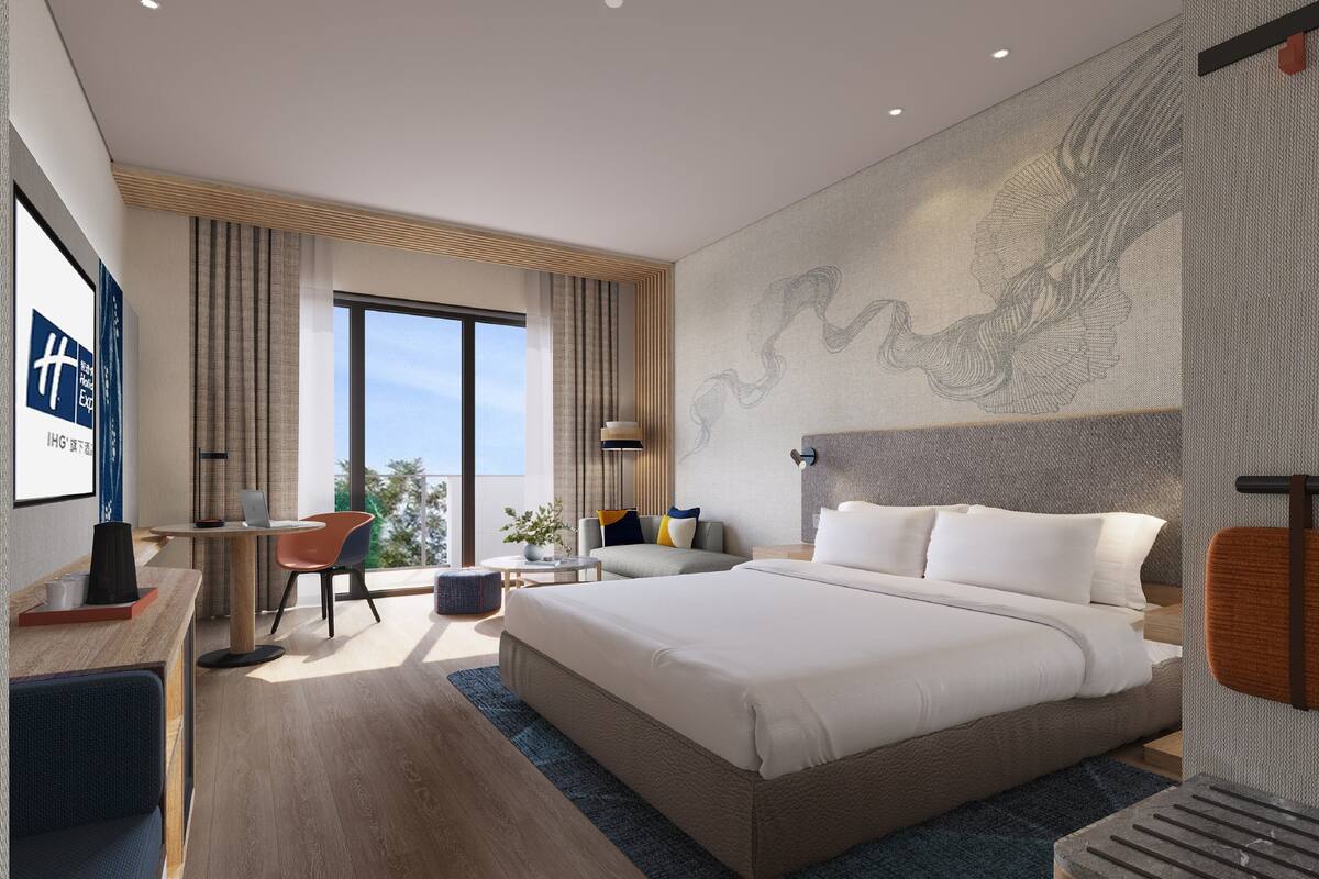 A modern hotel room with a large bed, a desk, and a view of the outdoors.