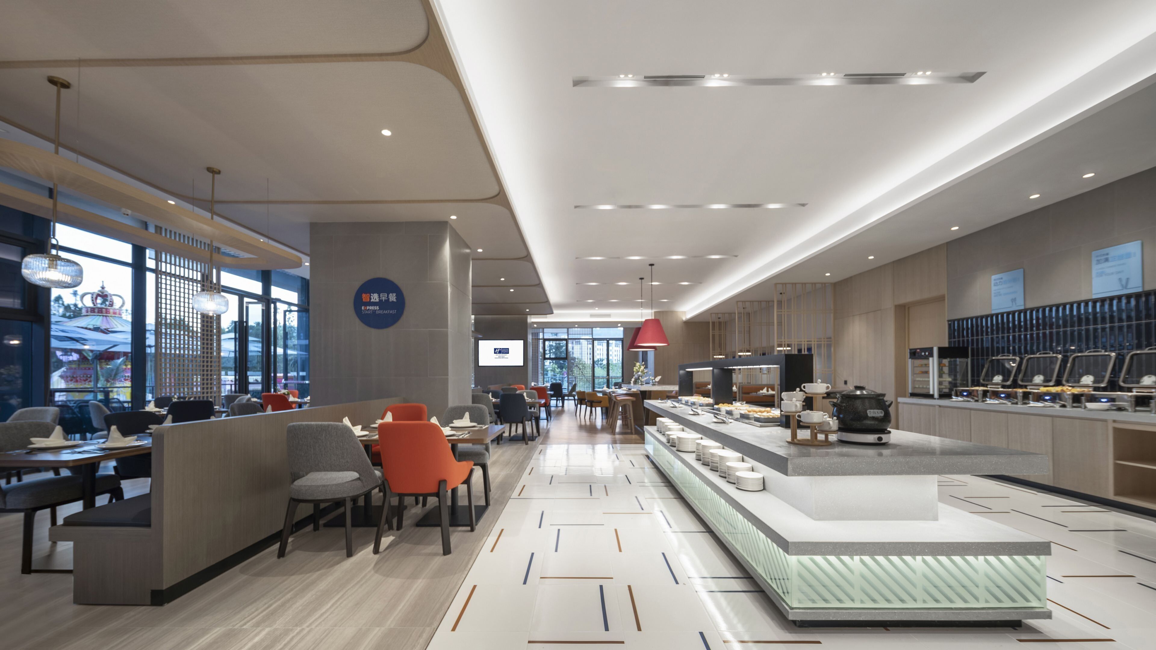 A modern hotel lobby with a reception desk, seating area, and a buffet setup.