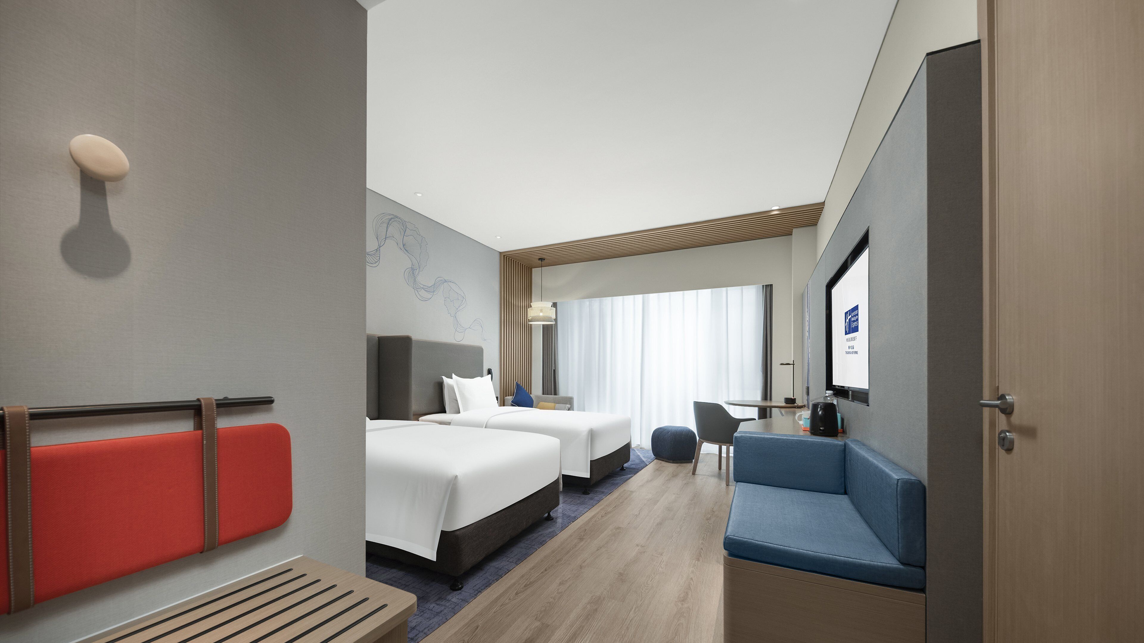 A hotel room with two beds, a seating area, a TV, and a wooden floor.