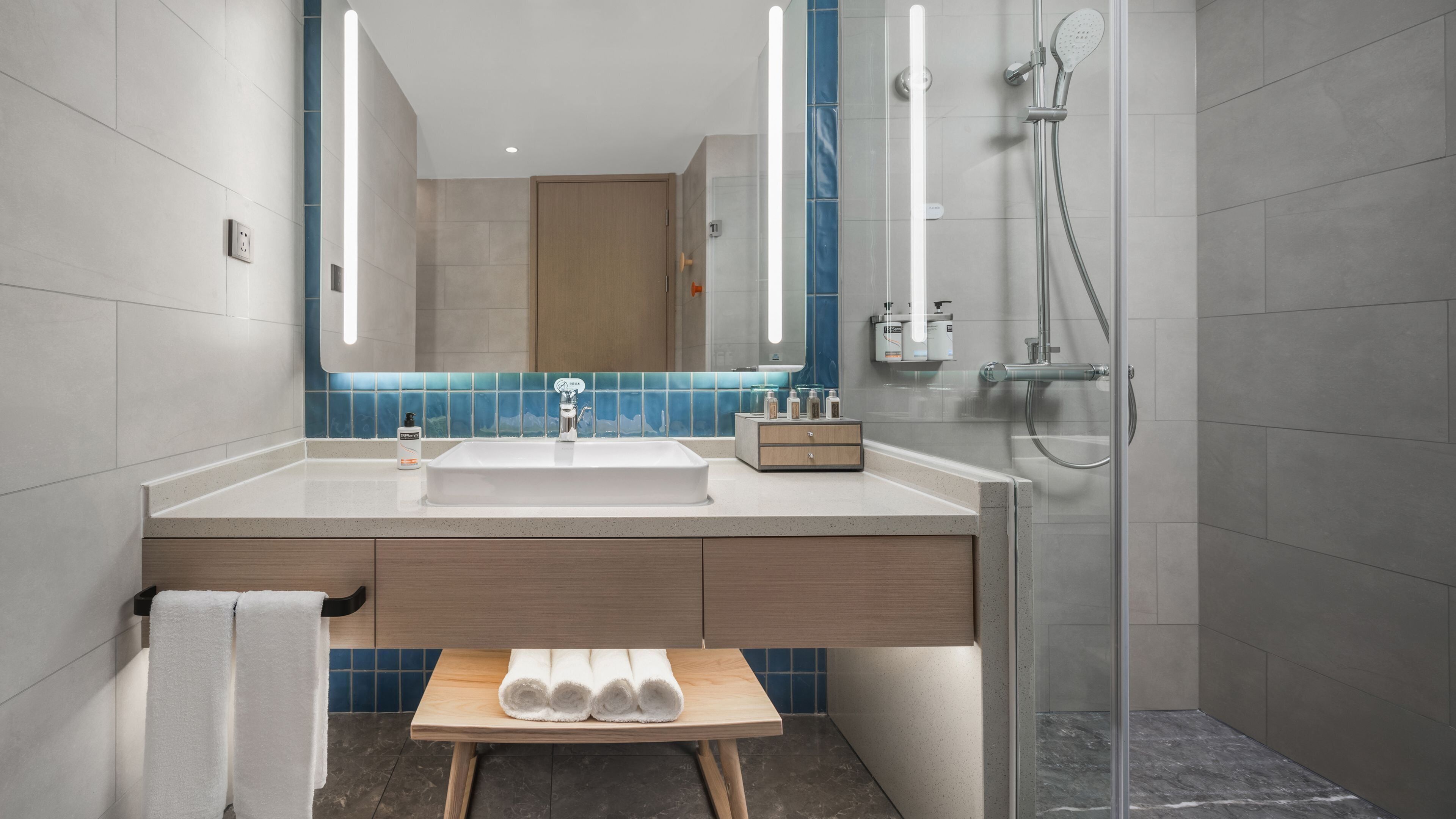 Un bagno moderno con uno specchio grande, un lavandino e una zona doccia.