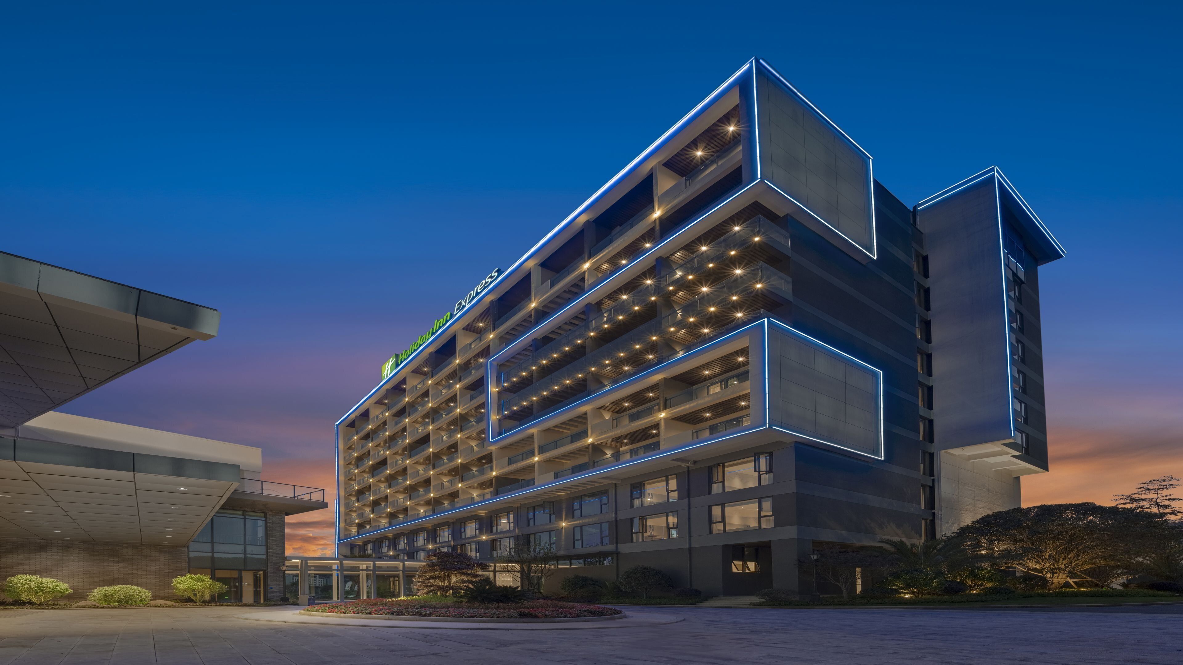 A modern hotel with multiple floors, a prominent sign, and a well-lit facade.