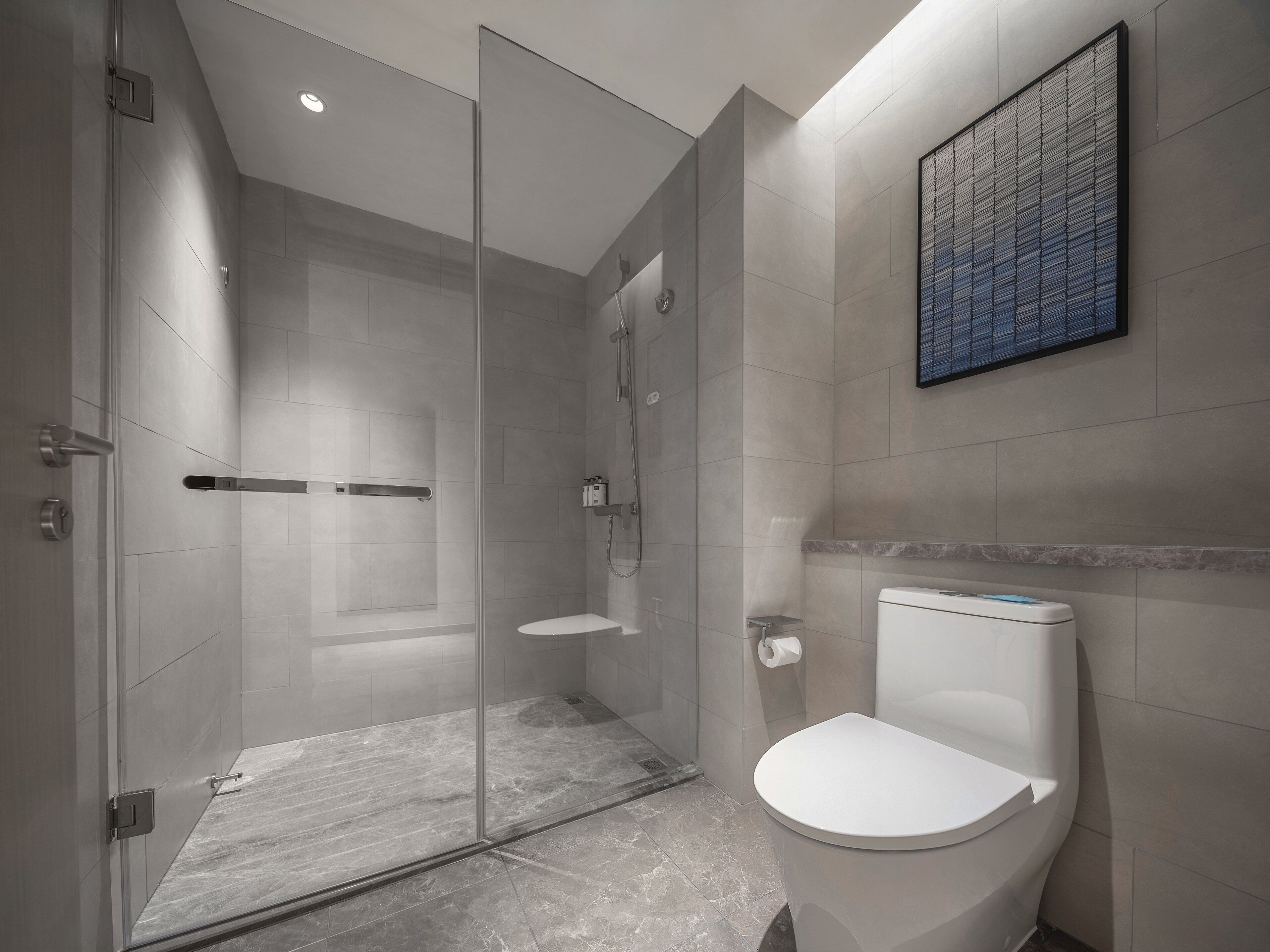 A modern bathroom with a glass-enclosed shower, a toilet, and a marble floor.