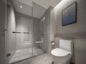 A modern bathroom with a glass-enclosed shower, a toilet, and a marble floor.