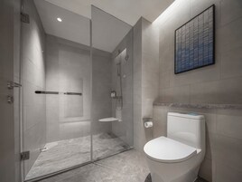 A modern bathroom with a glass-enclosed shower, a toilet, and a marble floor.