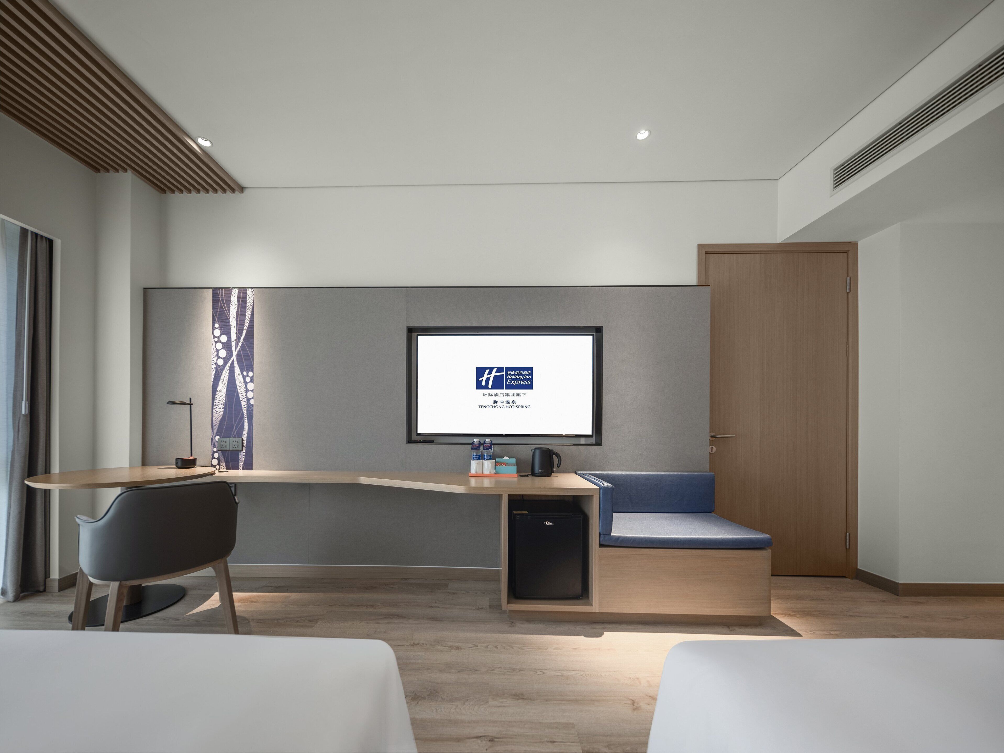 A modern hotel room with a desk, chair, and a bed.
