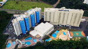 A high-rise hotel with multiple buildings, a swimming pool area with various water features, and a basketball court. - Suite Golden Dolphin Grand - EUEMCALDAS (Caldas Novas)