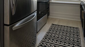 A kitchen with a stainless steel refrigerator, a built-in oven, and a window with a view of the outside.