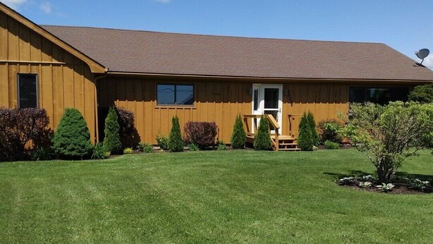 A two-story wooden building with a flat roof, a front porch, and a satellite dish.