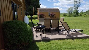 An outdoor patio with a grill, chairs, and a small table.