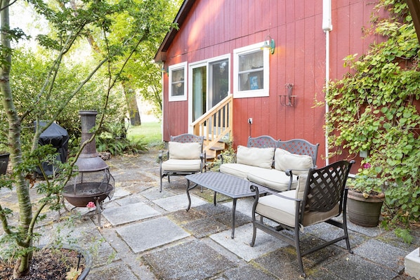 A red building with a covered porch, outdoor seating, and a fire pit. - The Farmhouse on 8 acres (Packwood)