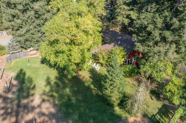 A residential property with a fenced yard, a red house, and a small shed.