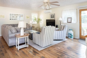 A living room with a sofa, armchair, coffee table, and a ceiling fan.
