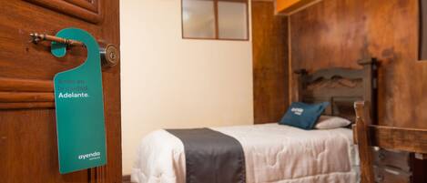 Una habitación de hotel con cama, muebles de madera y una puerta con un letrero verde.