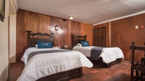 Une chambre avec deux lits, des murs en bois et un plancher en bois.