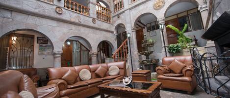 A spacious lobby with leather sofas, a wooden coffee table, and a staircase leading to an upper level.