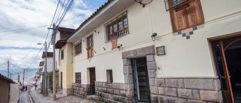 Una estrecha calle adoquinada flanqueada por edificios tradicionales con fachadas de piedra y contraventanas de madera.
