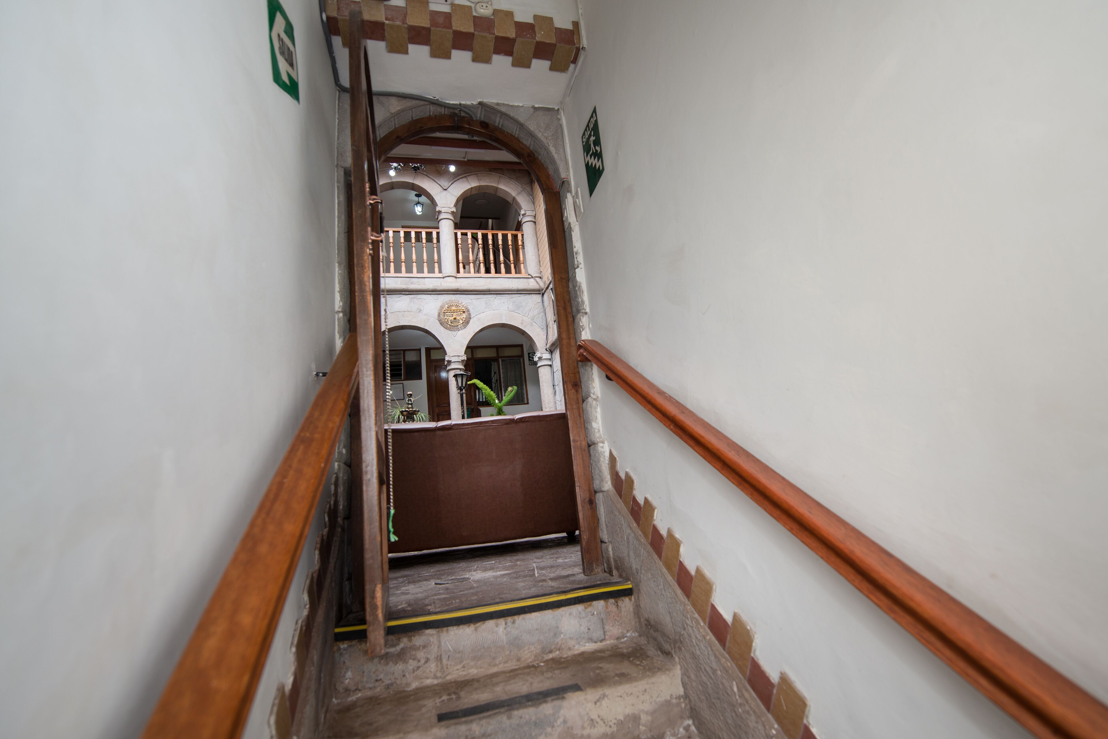 A narrow staircase with wooden handrails and a small balcony on the upper landing.