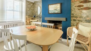 Ein Essbereich mit Steinwand, blauer Akzentwand, Kamin und einer Korbschrank-Chandeliebre.