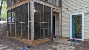 Un porche cubierto adosado a una casa, con una puerta y dos macetas.