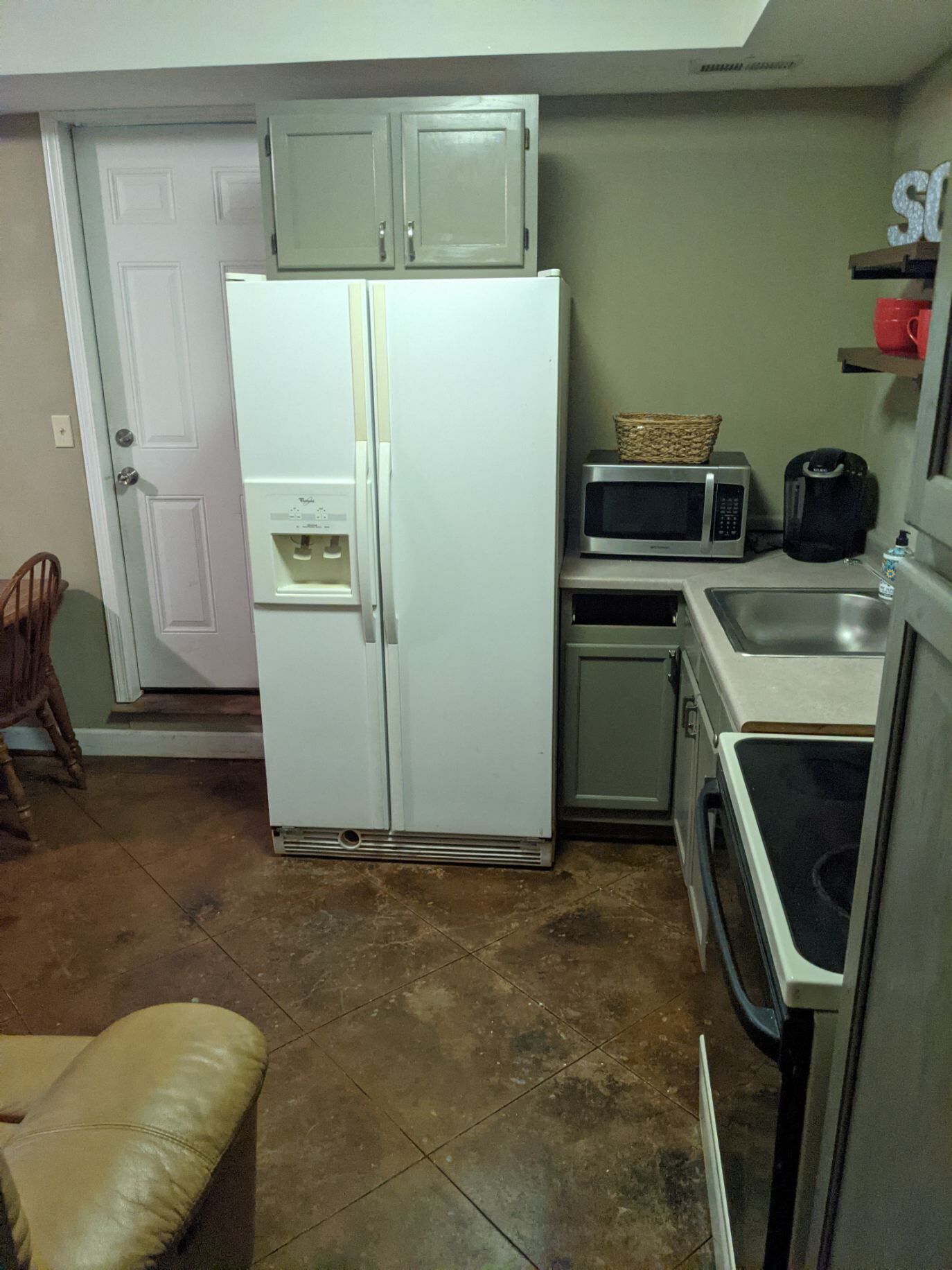 A compact kitchen with a white refrigerator, a microwave, a coffee maker, and a dishwasher.
