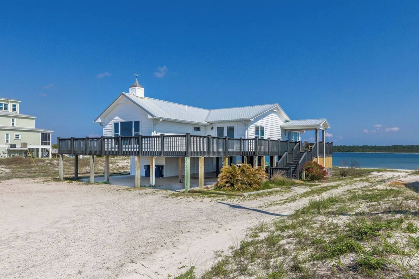 A beachfront house with a wooden deck and a covered porch.