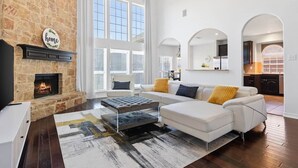 A living room with a fireplace, white sofas, and a large window.