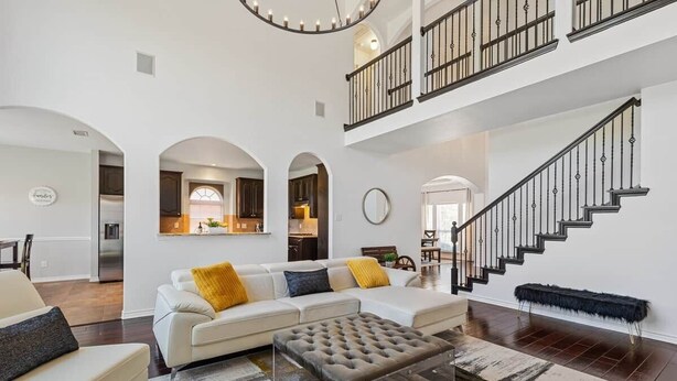 A spacious living area with a staircase, a sofa set, and a dining area.