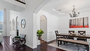 A dining area with a dark wooden table, bench, and chandelier.