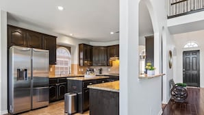 A kitchen with dark wood cabinets, stainless steel appliances, and a granite countertop island.